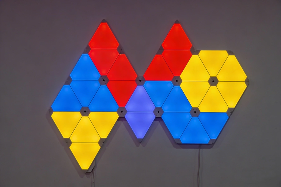 Small gaming room with RGB hexagon wall light layout, modern gaming setup design featuring immersive ambient lighting and stylish geometric LED panels by Gaming Hexagon Lights.